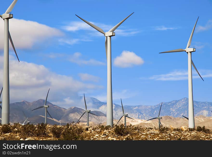 Wind turbines in a desert setting with mountains in the background