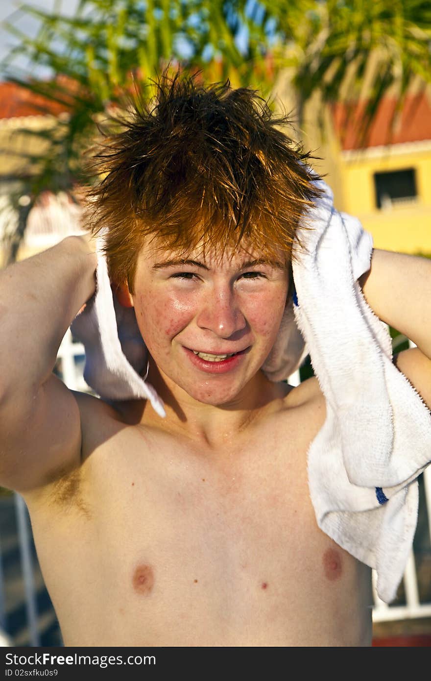 Boy with red hair using a towel after swimming in a pool. Boy with red hair using a towel after swimming in a pool