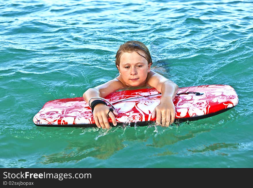 Boy is crawling on the surfboard