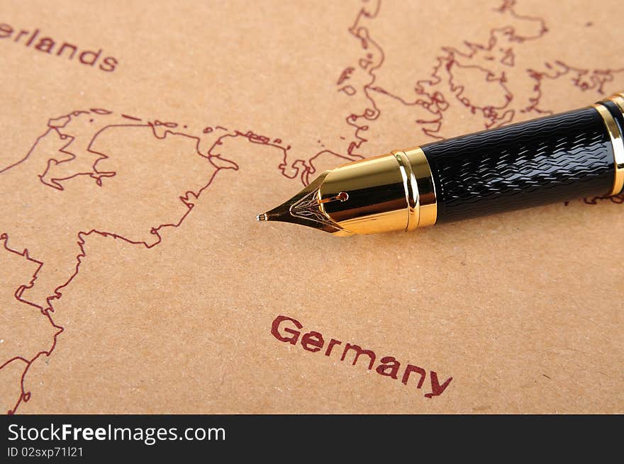 A fountain pen with golden top putting on a European map, means business and travel concept. A fountain pen with golden top putting on a European map, means business and travel concept.