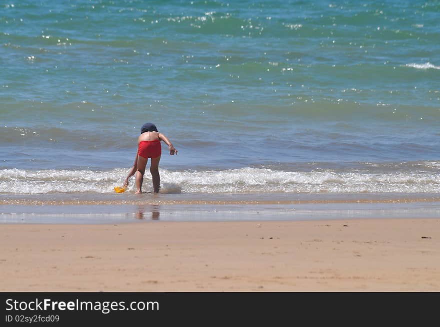 Young boy plays at the shore on a beach. Young boy plays at the shore on a beach.