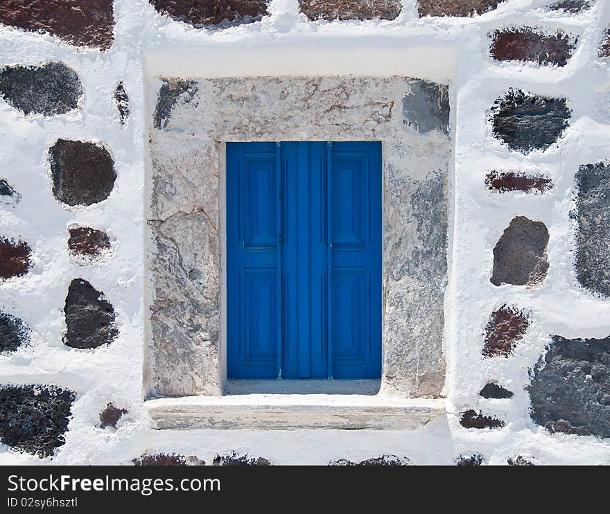 Stonewall with blue window from a house in Santorini Island. Stonewall with blue window from a house in Santorini Island