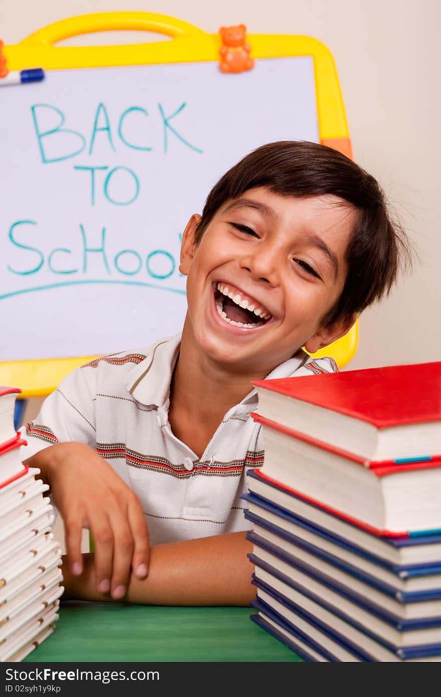 Smiling boy with school books on the table