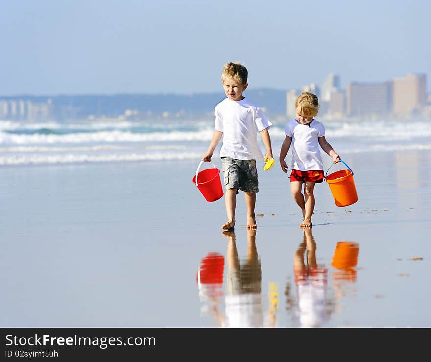 Brother and sister walk along the ocean edge looking for shells. Brother and sister walk along the ocean edge looking for shells