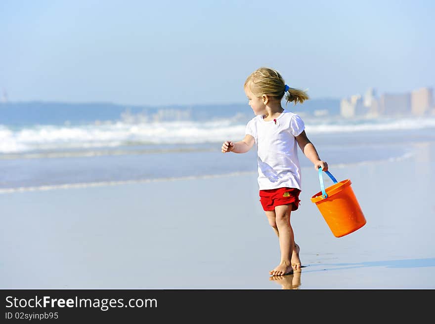 Cute little girl walks along the ocean edge looking for shells. Cute little girl walks along the ocean edge looking for shells