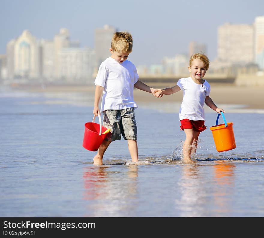 Young children walk along the ocean edge looking for shells. Young children walk along the ocean edge looking for shells