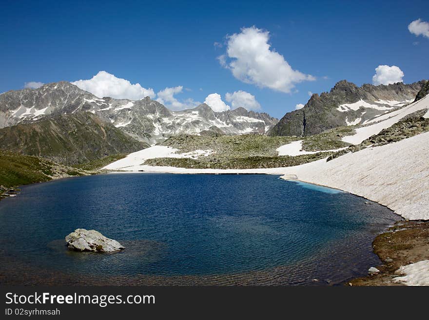 Blue lake surounded with snow and rocky mountains. Blue lake surounded with snow and rocky mountains