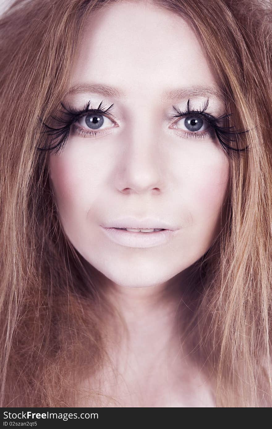 A glamorous, high fashion woman with exaggerated eyelashes stares into camera. Vertical shot. A glamorous, high fashion woman with exaggerated eyelashes stares into camera. Vertical shot.