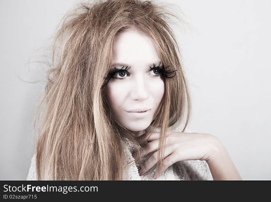 A glamorous, high fashion woman with exaggerated eyelashes and wild hair stares off into distance. Horizontal shot. A glamorous, high fashion woman with exaggerated eyelashes and wild hair stares off into distance. Horizontal shot.