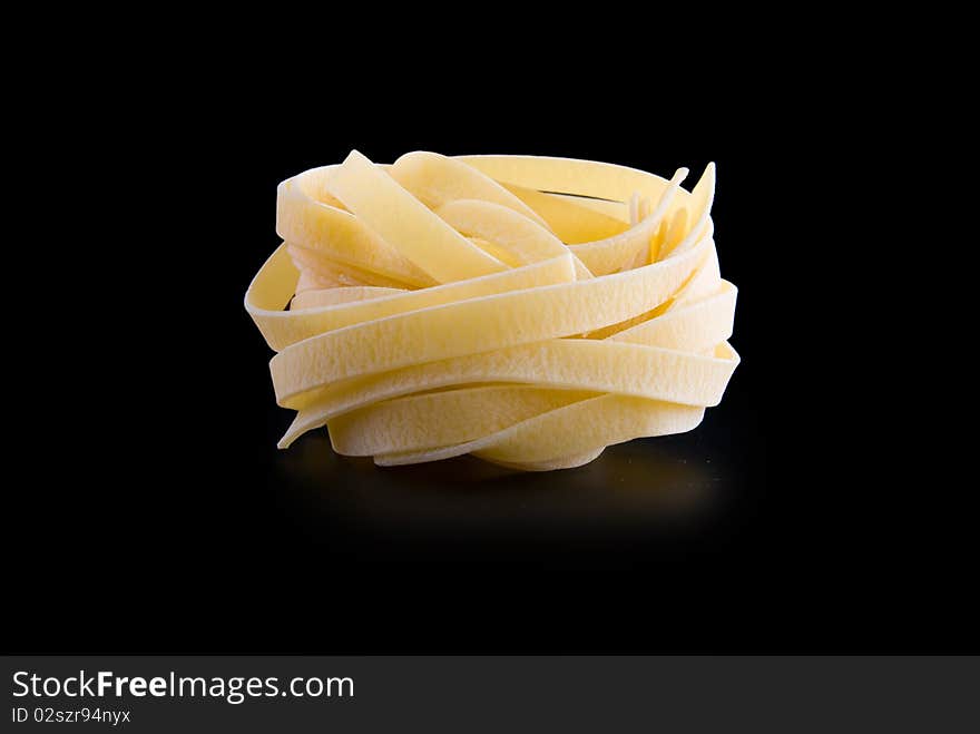 Raw dry nest pasta with reflection isolated on black