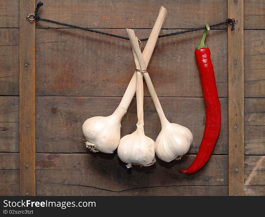 Garlic and chili pepper hanging with rope on wooden background. Garlic and chili pepper hanging with rope on wooden background