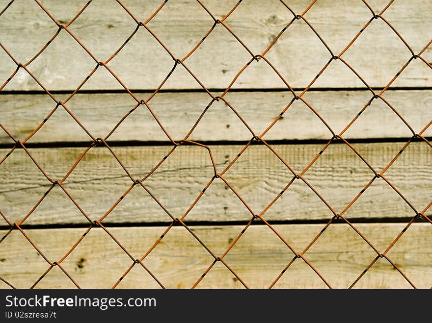 Red mesh-fence against the background of old woods