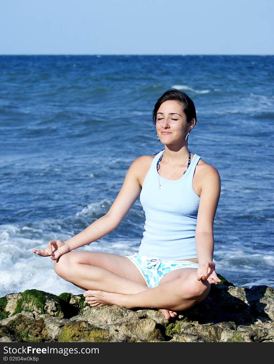 Portrait of a young woman meditating on rocks near the seaside. Portrait of a young woman meditating on rocks near the seaside