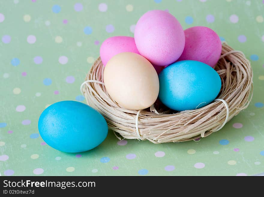 Colorful eggs in the nest on polka dot background