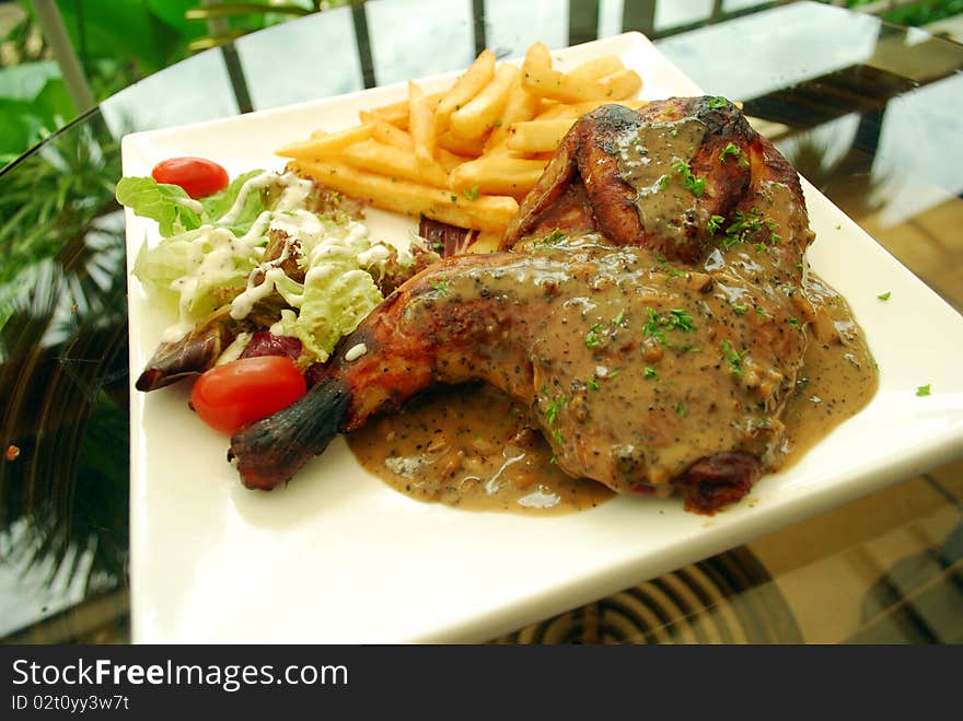 Delicious chicken drumstick with french fries on a plate