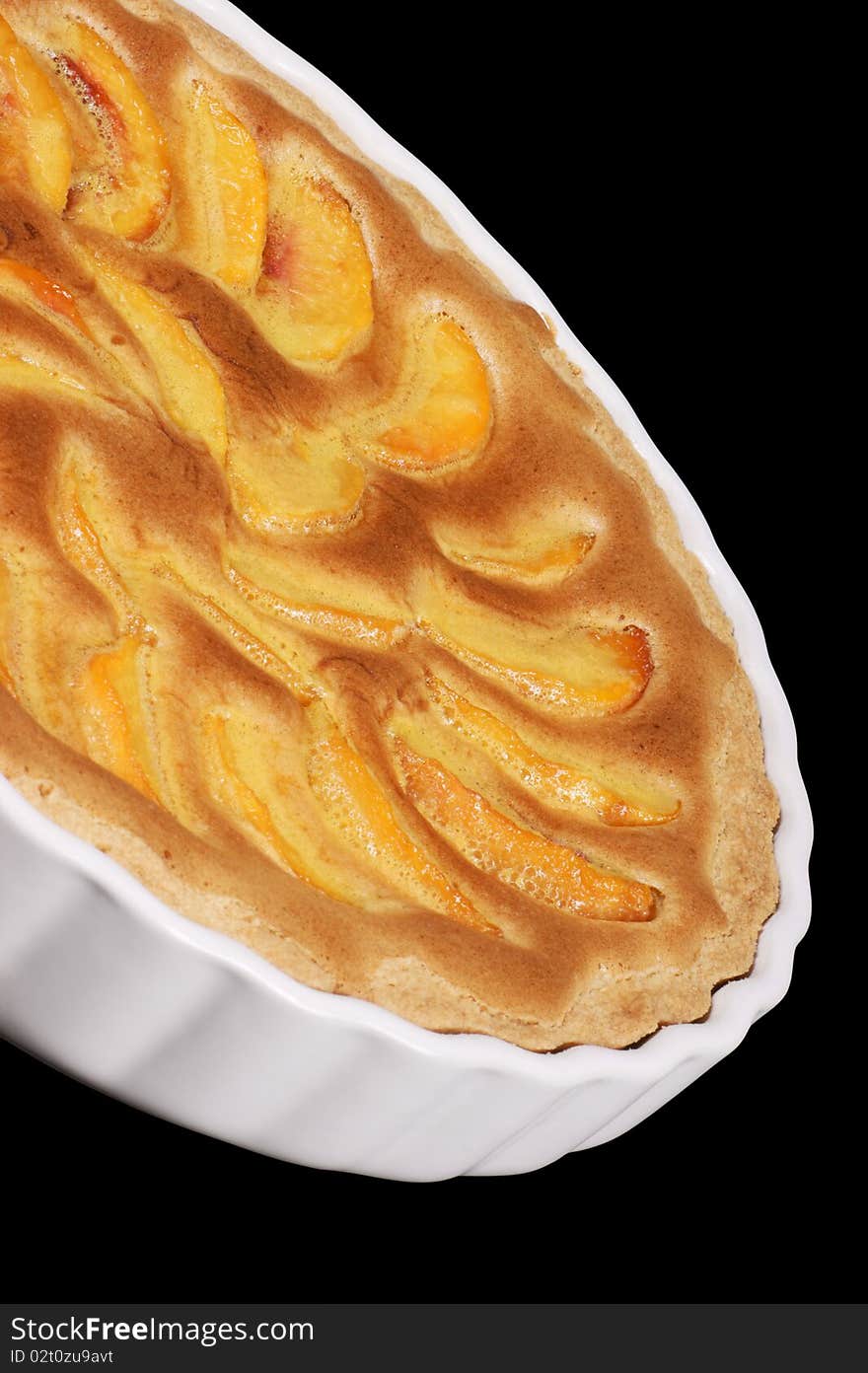 Peach tart in a white pottery cake tin. Isolated on black with clipping path.