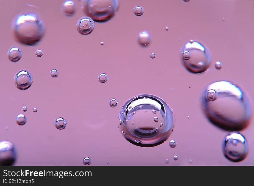 Bubbles of different sizes in pink liquid