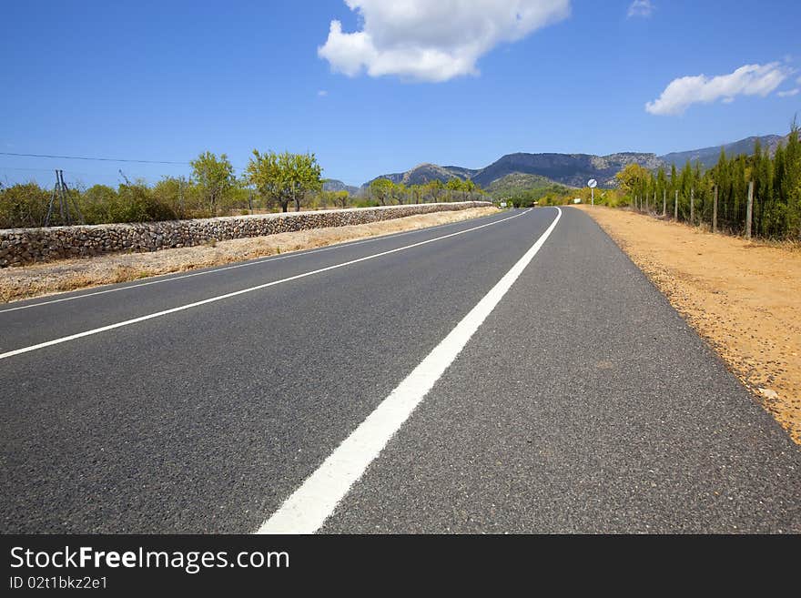 Straight highway road across non-urban landscape with blue sky and clouds. Straight highway road across non-urban landscape with blue sky and clouds