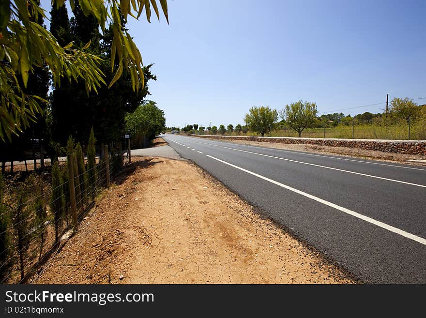 Highway road across non-urban summer landscape with blue sky and clouds. Highway road across non-urban summer landscape with blue sky and clouds