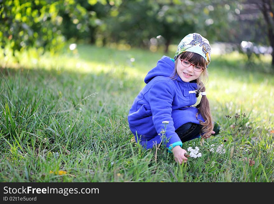 Nice little girl in blue coat picks up flowers