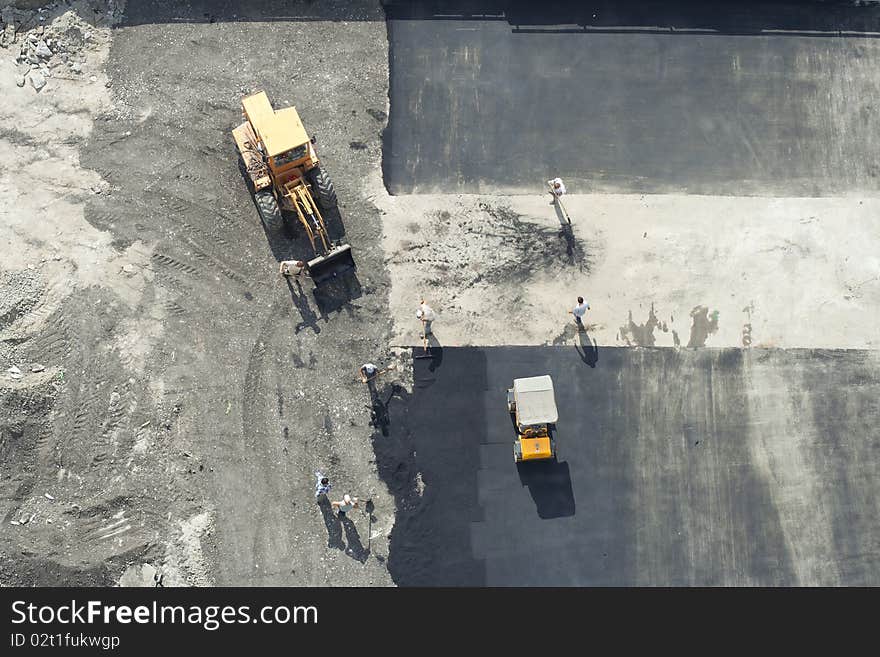 Workers repairing the road using road roller and excavator