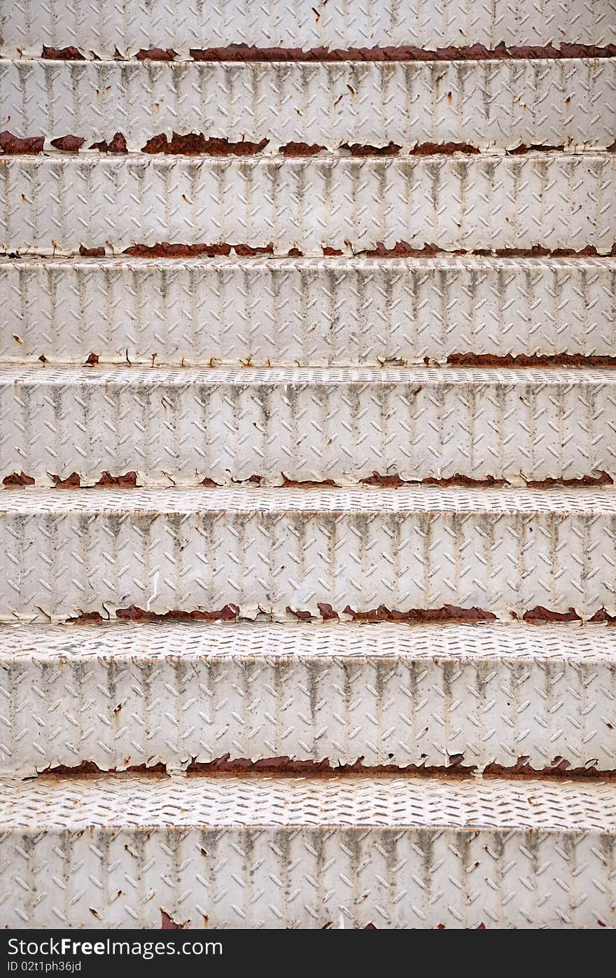 Rusty iron stairway with white painting, as repeated shape and texture.