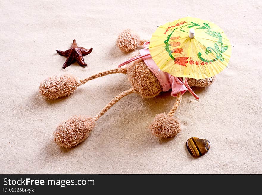 Plush toy under the beach umbrella on the sand