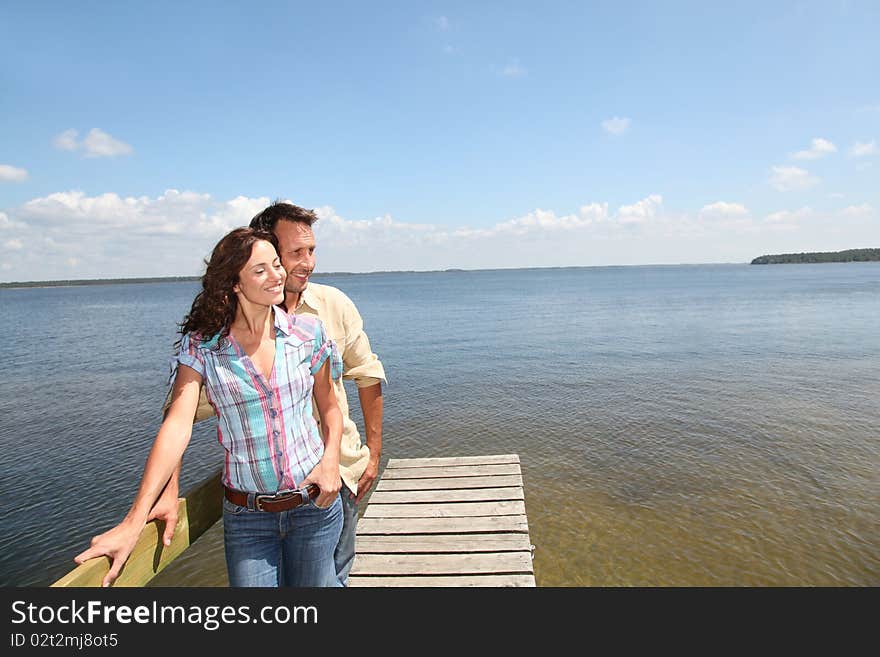 Loving couple standing on a pontoon by a lake. Loving couple standing on a pontoon by a lake