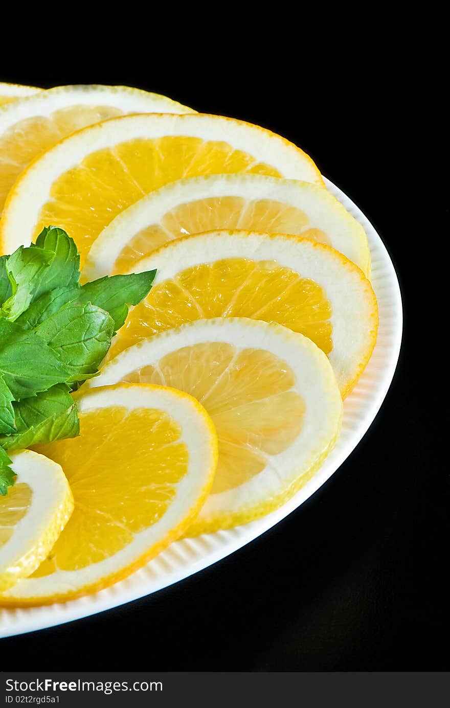 Slices of lemon and orange with mint leaves on black background