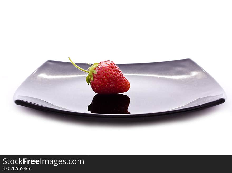 Red strawberry on black plate isolated on white