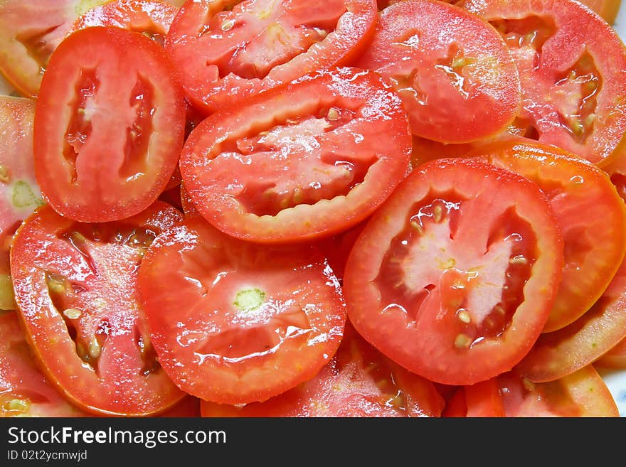 Pattern of Red Sliced tomatoes on plate with water drops texture using as background