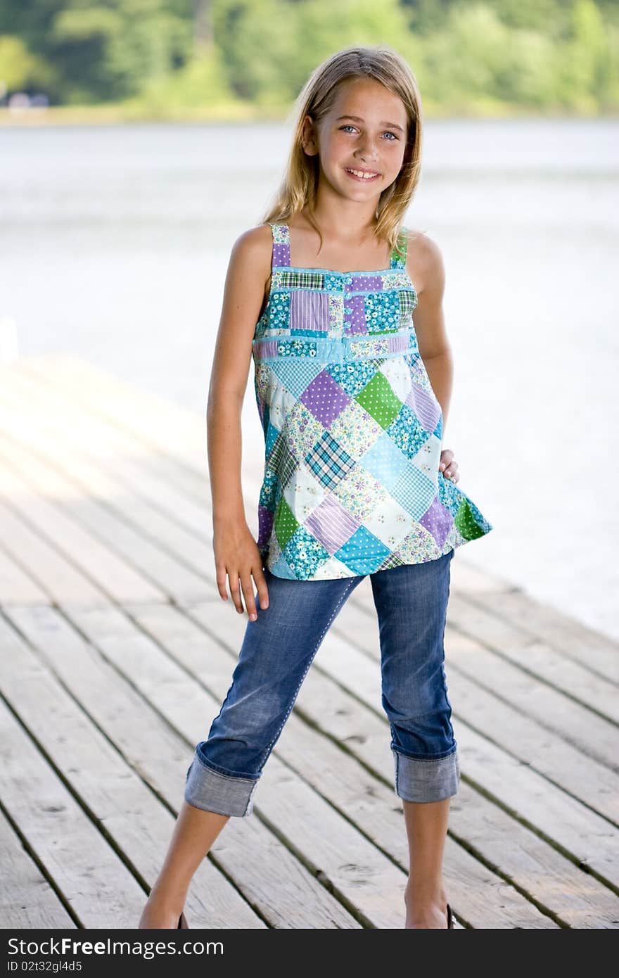 A young, pretty, preadolescent girl standing on a dock and smiling at the camera. A young, pretty, preadolescent girl standing on a dock and smiling at the camera.