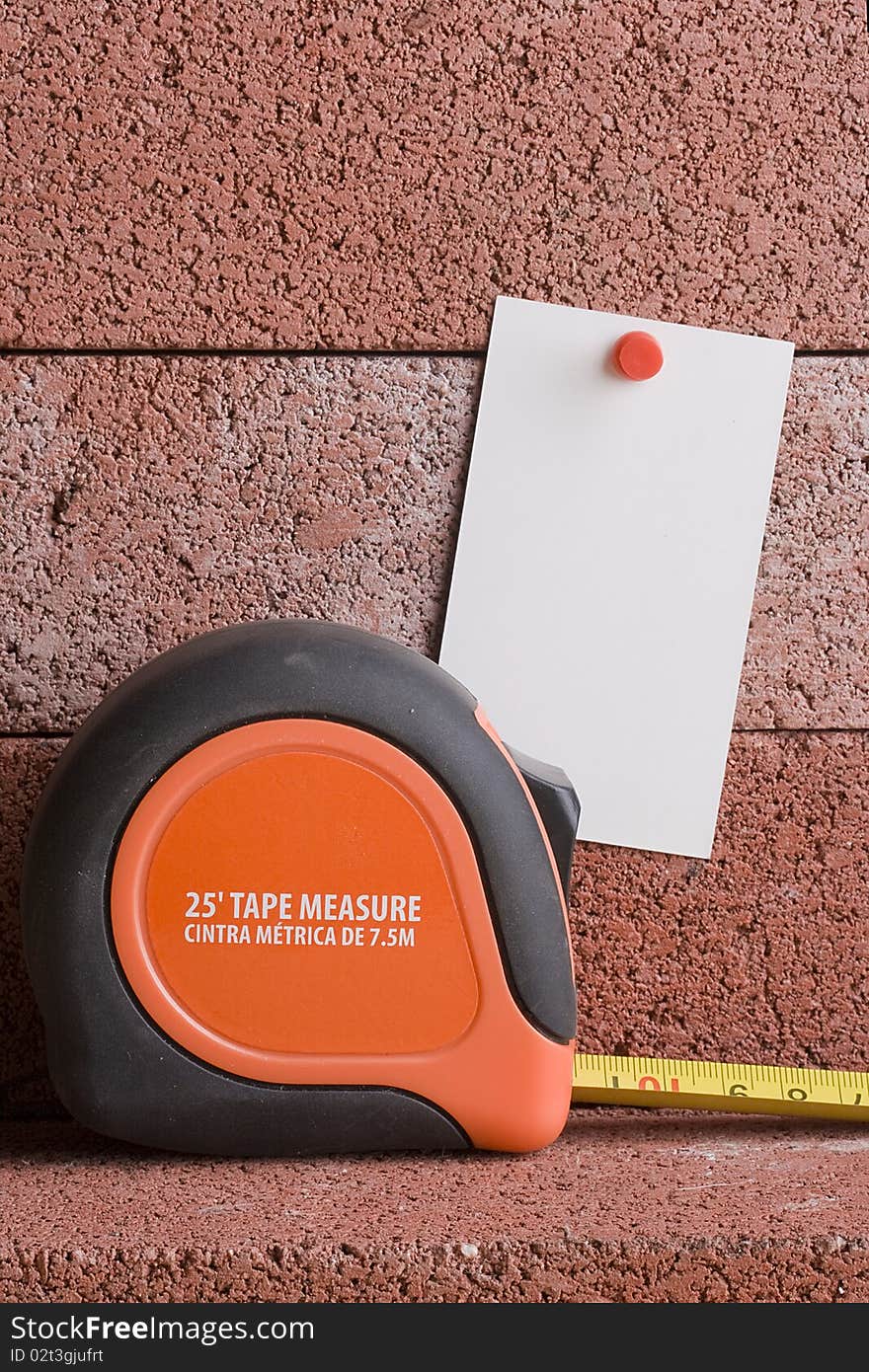 White piece of paper next to a tape measure. Add your text to the paper. White piece of paper next to a tape measure. Add your text to the paper.