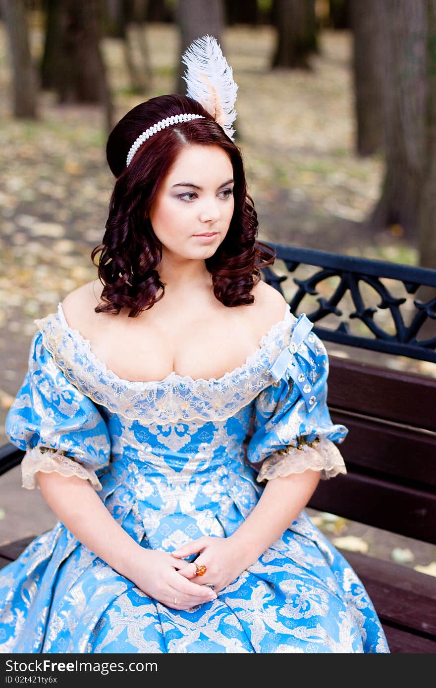 A portrait of lady in a blue baroque dress sitting on bench. A portrait of lady in a blue baroque dress sitting on bench