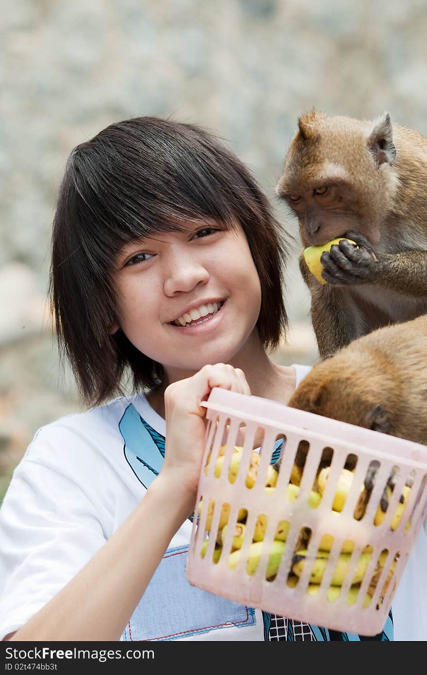 Girl with monkey, animal sits on shoulder and wait for banana