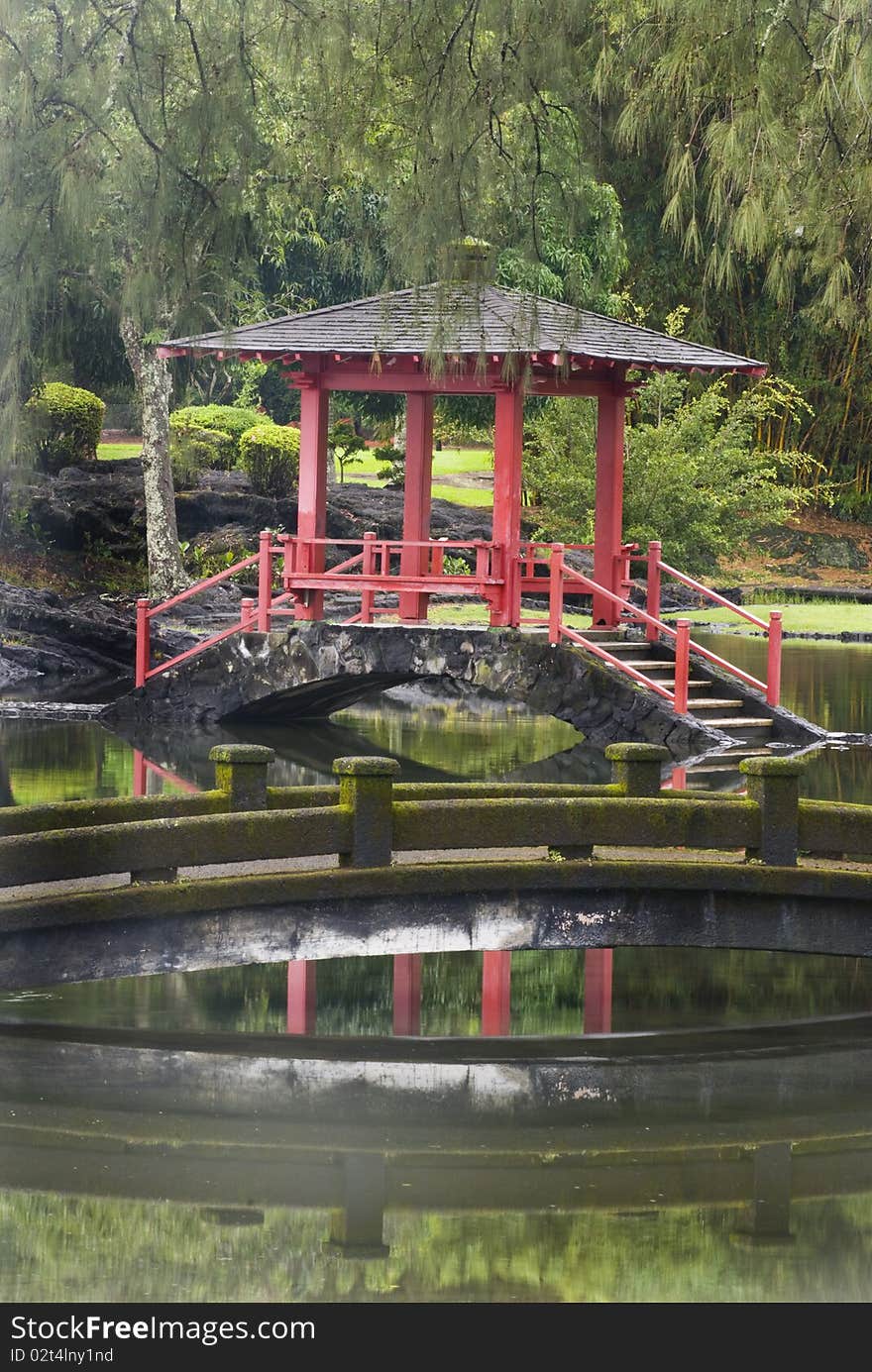 Garden gazebo in early morning fog surrounded by lush green vegetation and water.