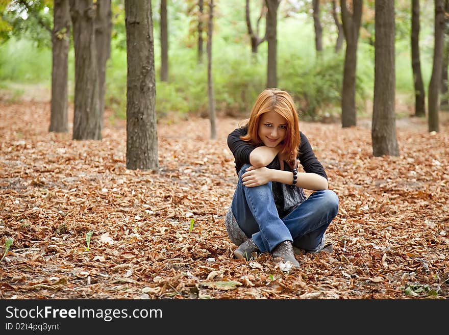 Beautiful red-haired girl in autumn park. Outdoor photo.