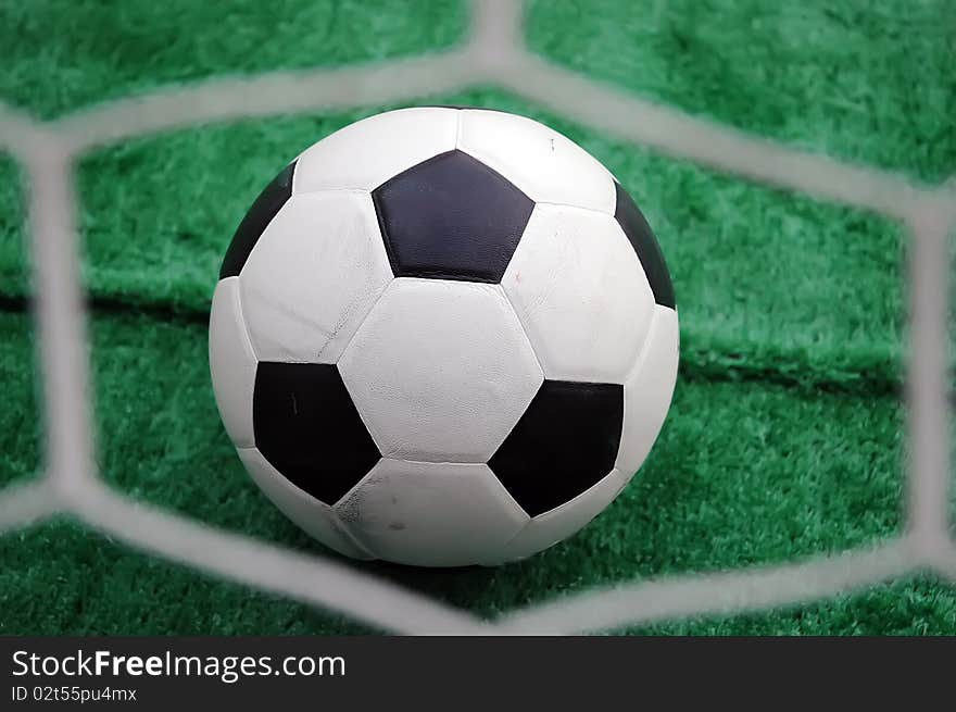 Soccer ball against the goal net in the grass. See more soccer photos in my portfoli. Soccer ball against the goal net in the grass. See more soccer photos in my portfoli