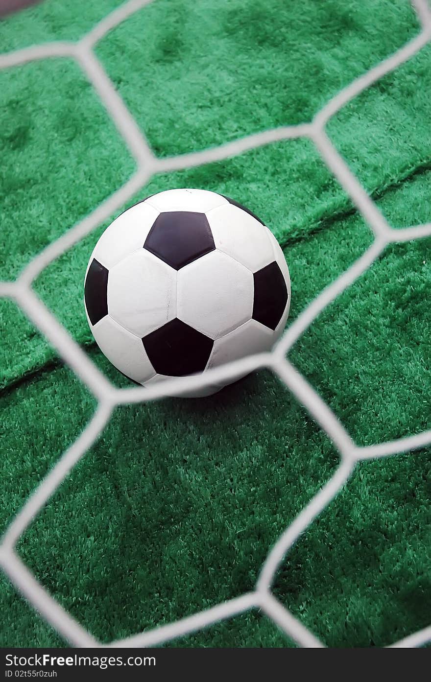 Soccer ball against the goal net in the grass. See more soccer photos in my portfoli. Soccer ball against the goal net in the grass. See more soccer photos in my portfoli