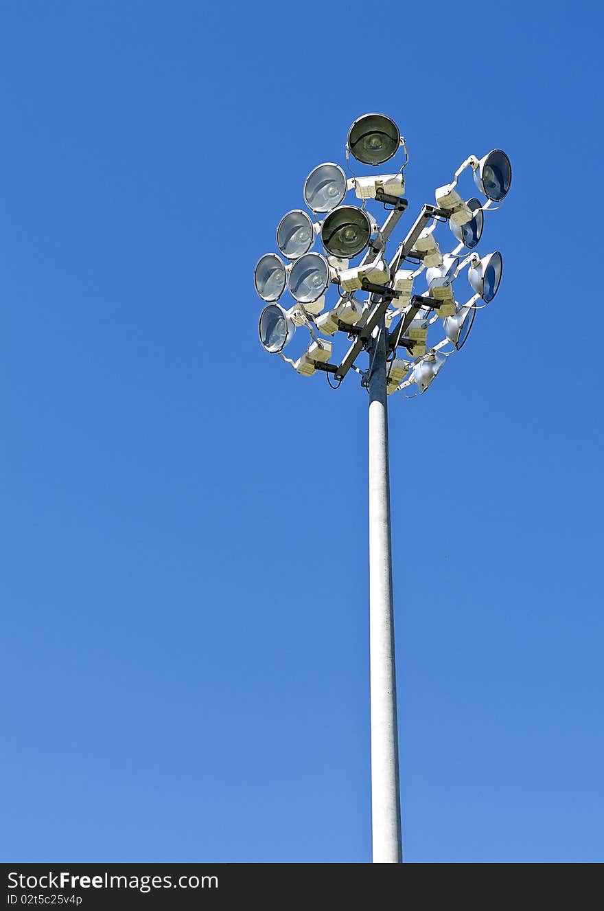 Stadium lights in daytime against bright blue sky. Stadium lights in daytime against bright blue sky