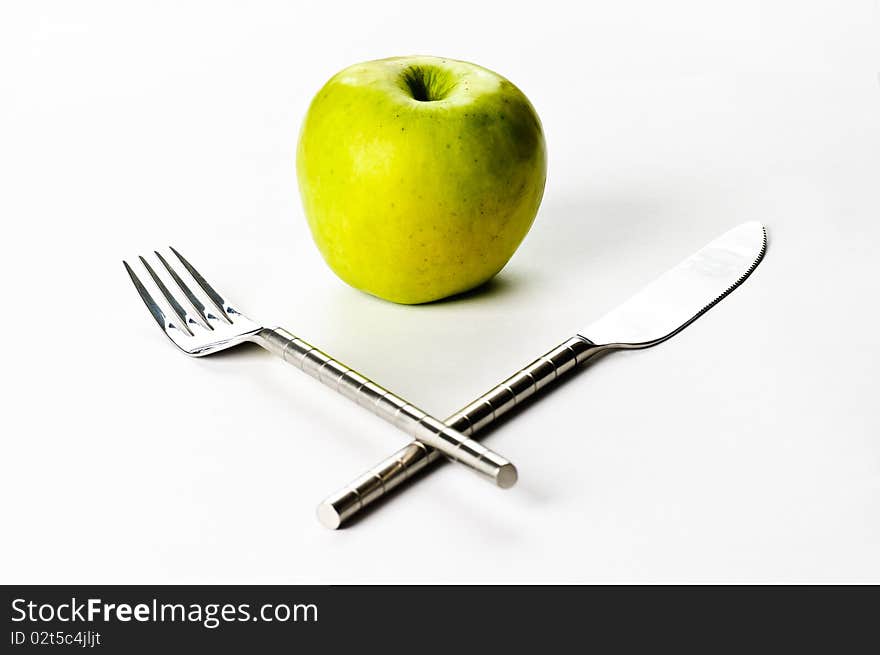 A knife, a fork and an apple on a white background. A knife, a fork and an apple on a white background