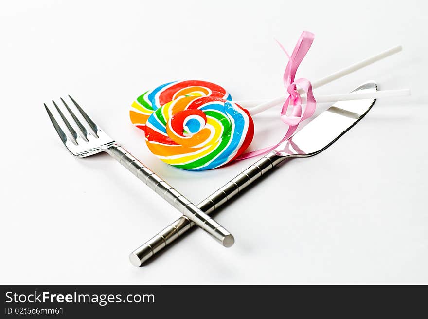 A knife, a fork and an couple of lollipops on a white background. A knife, a fork and an couple of lollipops on a white background