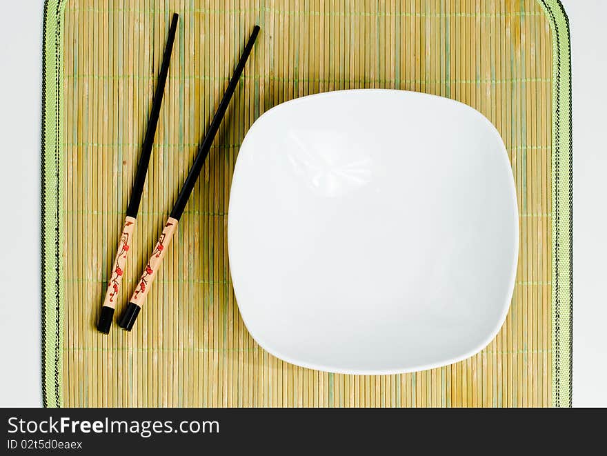 Two chop sticks and a white bowl. Two chop sticks and a white bowl.