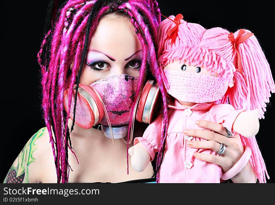 Cosplay young woman in respirator holding a doll over black background. Cosplay young woman in respirator holding a doll over black background.