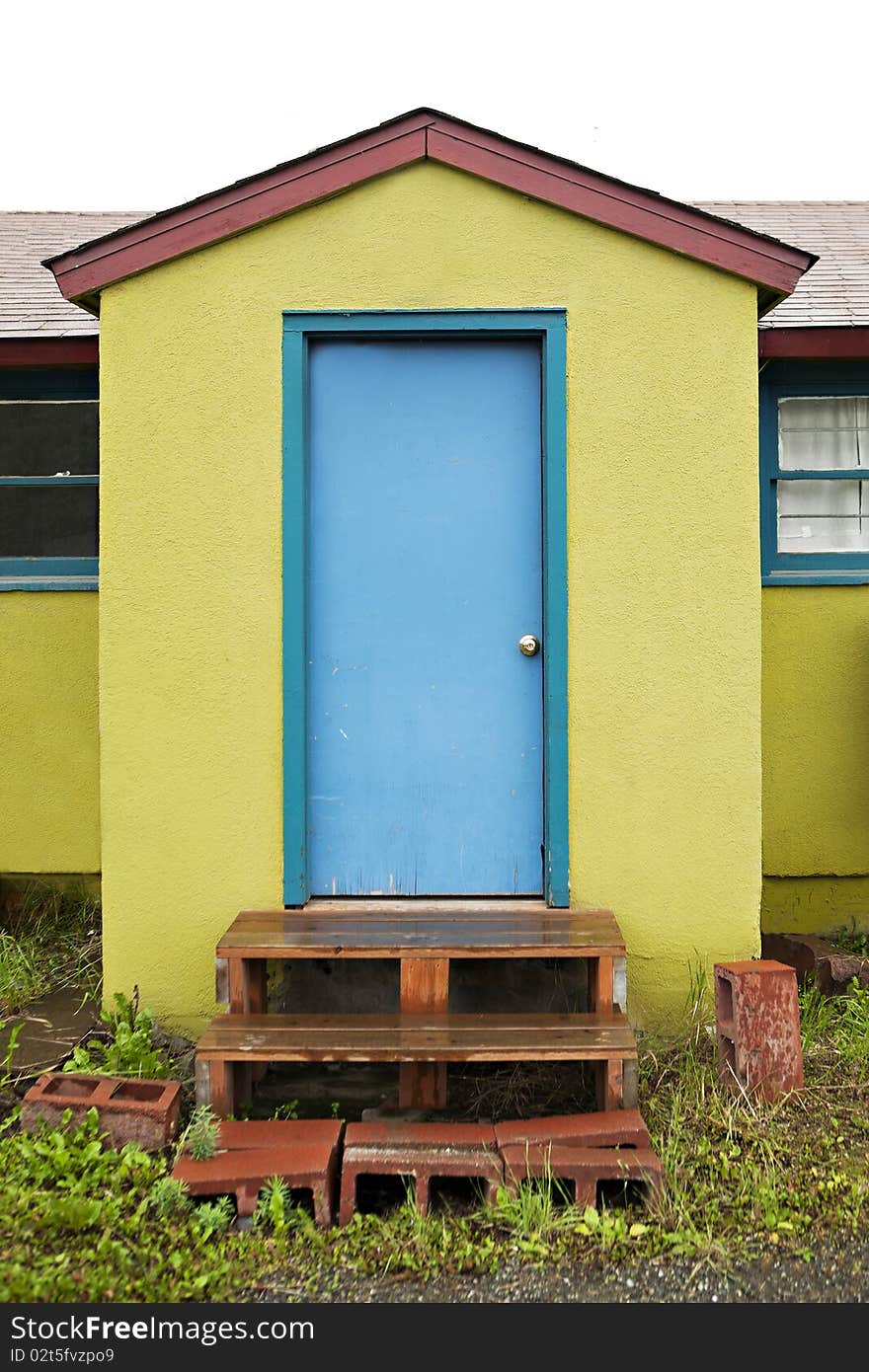 A small green building with a bright blue door. A small green building with a bright blue door.