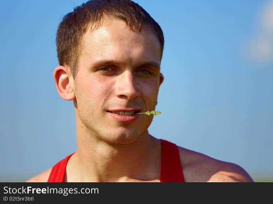 Portrait of young man with a blade grass in his mouth