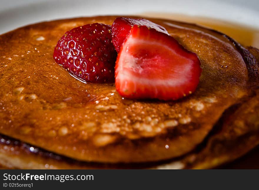 A breakfast of strawberries over pancakes, with syrup. A breakfast of strawberries over pancakes, with syrup.