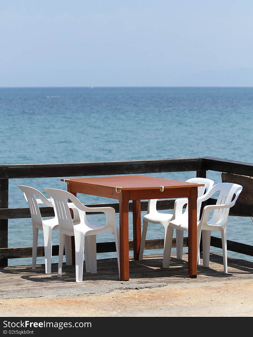 A table and four chairs in sunny and peacefully place by the sea. A table and four chairs in sunny and peacefully place by the sea