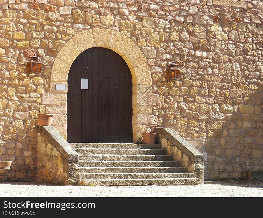 Medieval castle entrance with wooden door and steps in a bright day