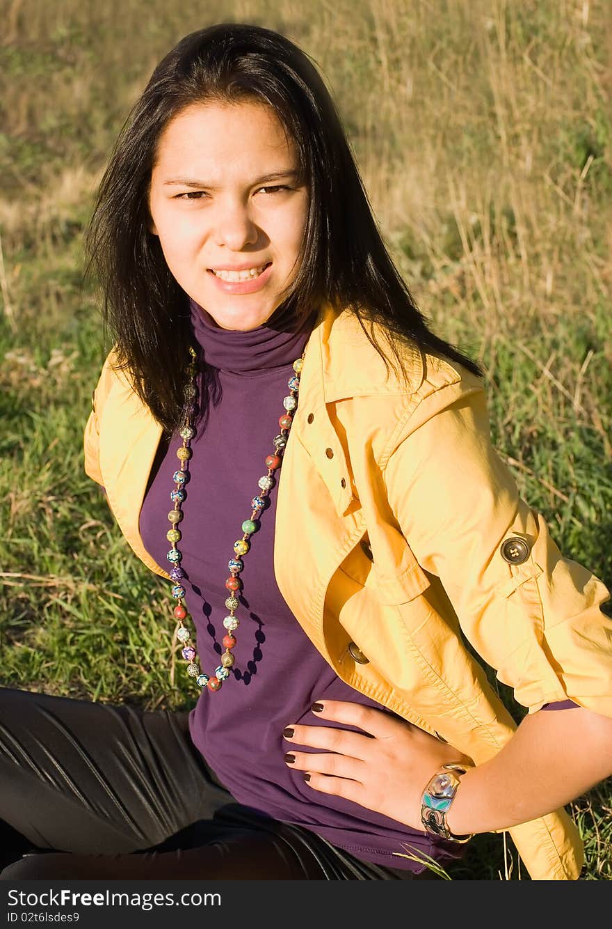 The young woman sits on a lawn and angrily speaks. The young woman sits on a lawn and angrily speaks